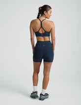 woman wearing a blue slim racerback bra and blue 3" biker shorts against a plain background.